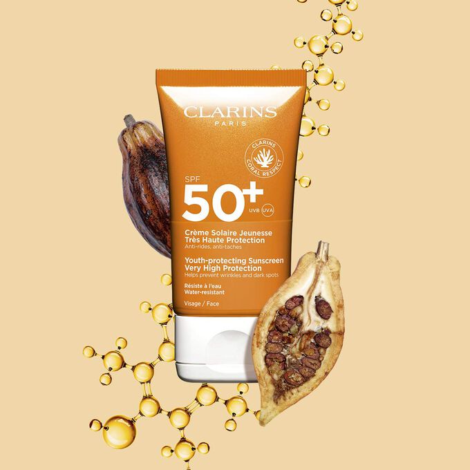 Plan produit du tube orange foncé de crème solaire SPF50 waterproof à côté de fèves de cacao sur un arrière-plan orange clair